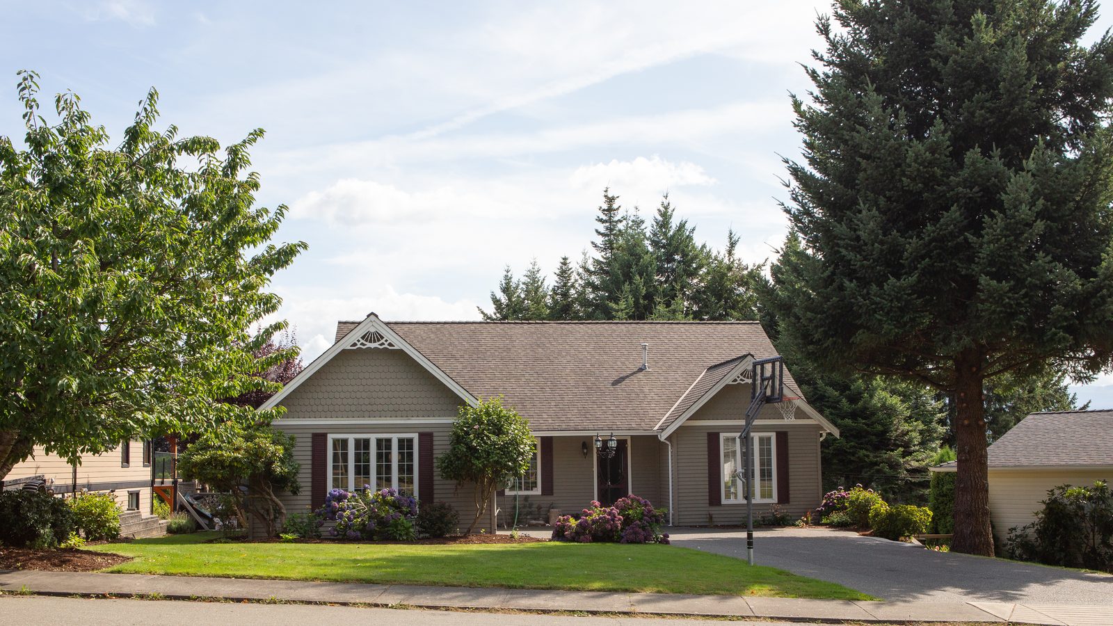 A single-story home with mature trees on a quiet residential street