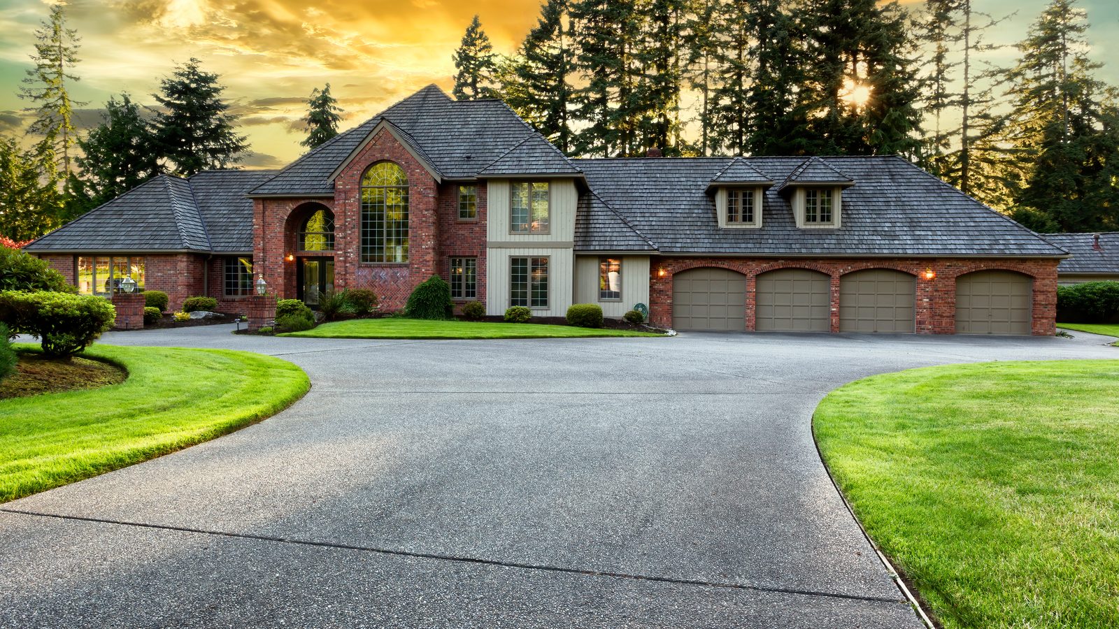 A large home at golden hour with a curved driveway