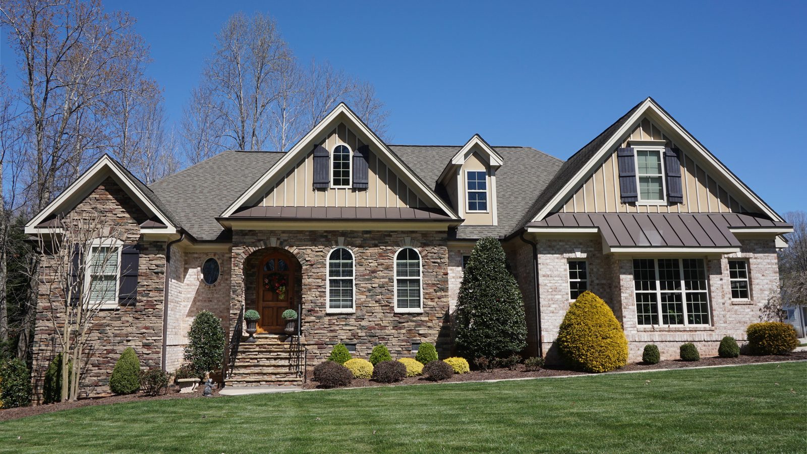 A single-family home with a stone and brick exterior on a clear day
